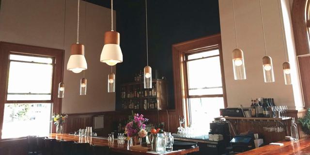Interior of en Rama, with tall windows and a warmly lit bar